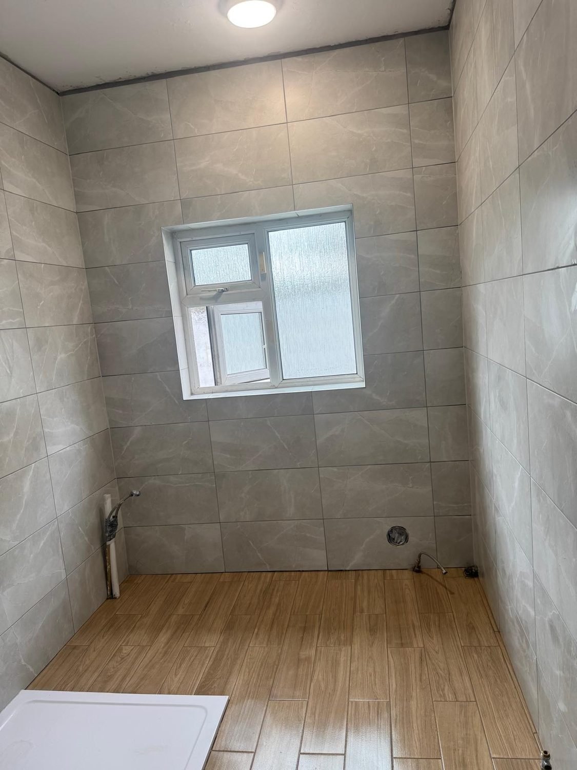 Bathroom with marble-effect walls and wood-effect floor tiling in Cork